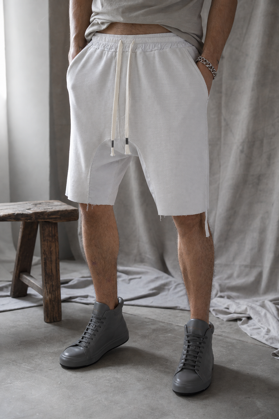 AITO Textured Drop-Crotch Shorts in Stone — front view on model, waffle-knit body with an off-white drawstring and low drop-crotch cut