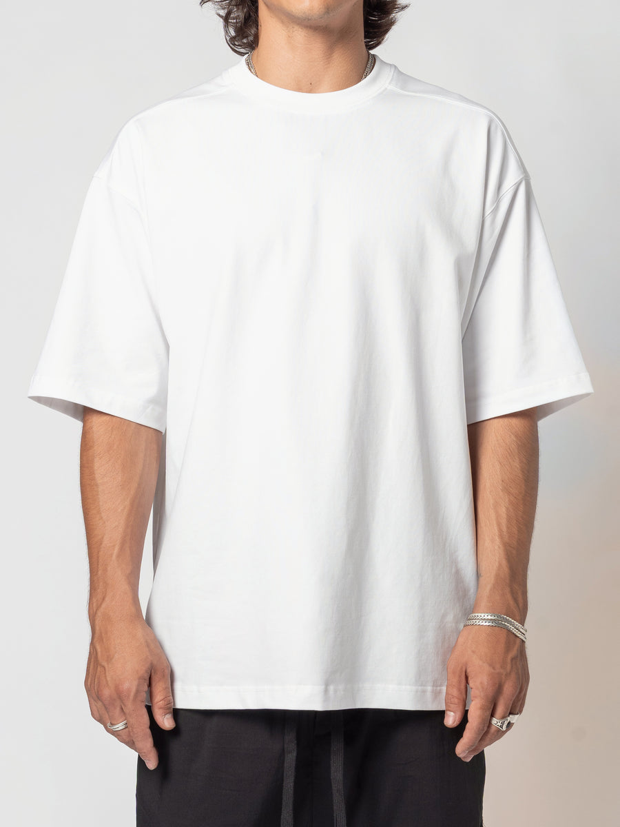 AITO Oversized Cotton T-Shirt in White — front view of the torso, body angled a fraction to one side, arms loose and a silver bangle showing at the wrist