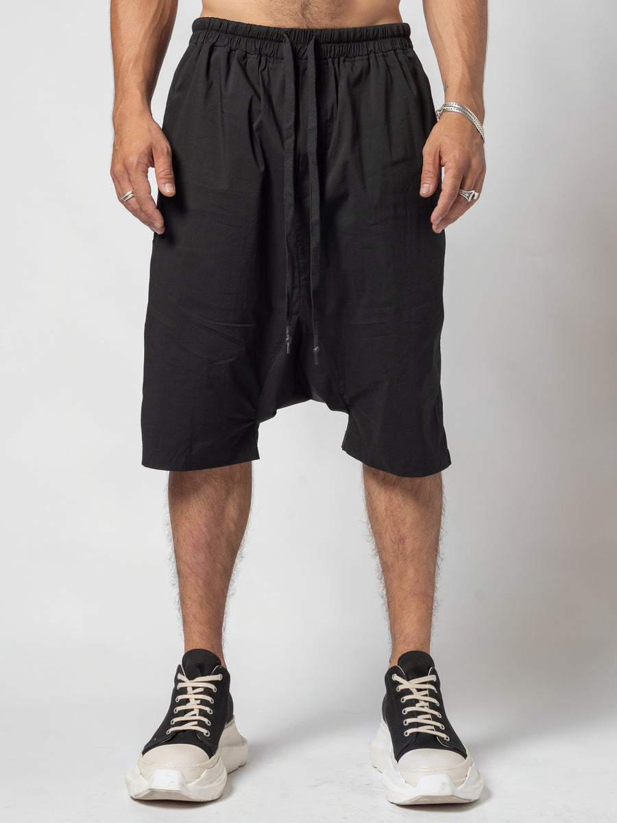 AITO Drop-Crotch Cotton Shorts in Black — front view, full length from the waist to the shoes, hands resting at the sides and the drawcord hanging down the centre