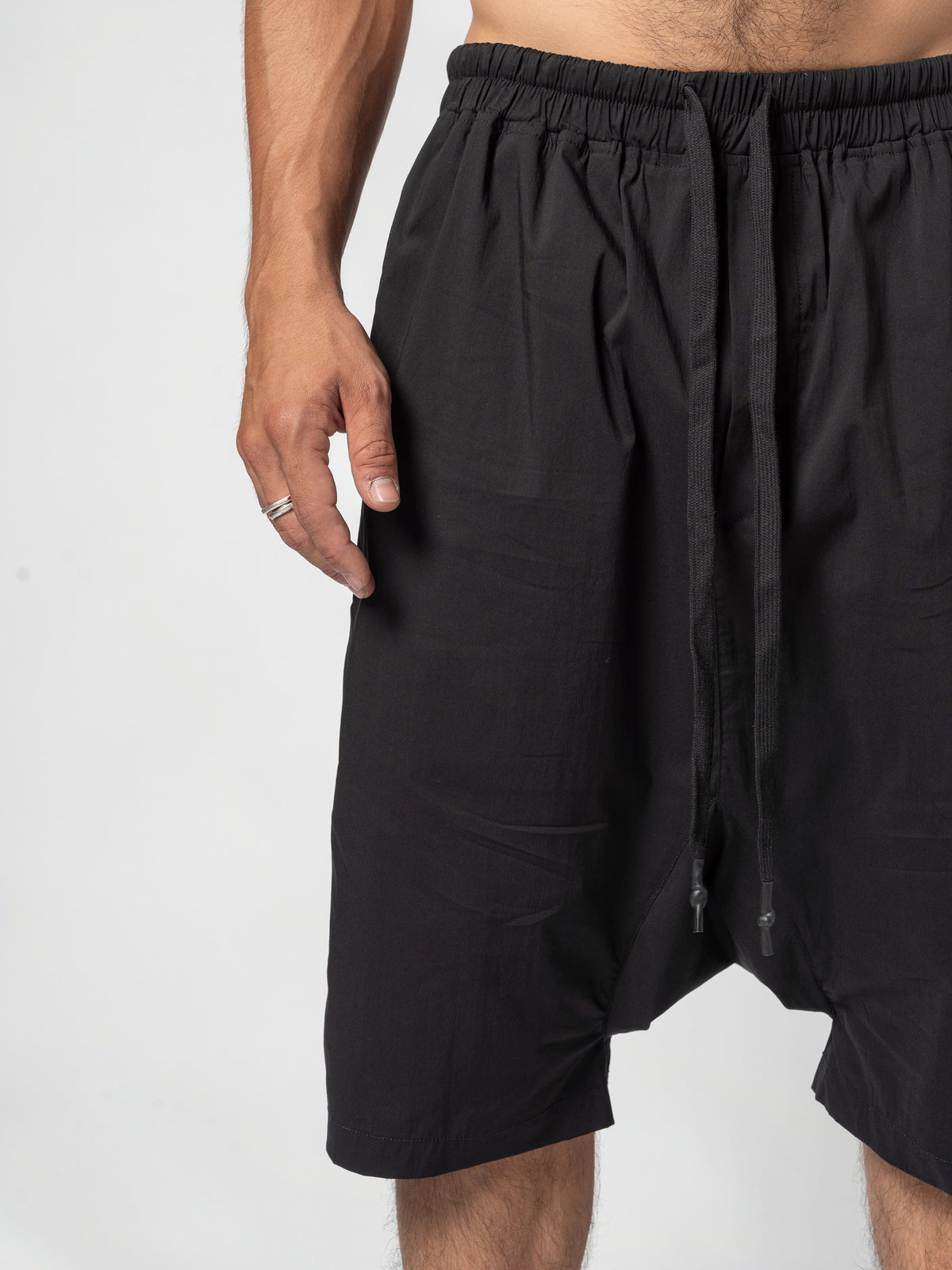 AITO Drop-Crotch Cotton Shorts in Black — front crop from the gathered waistband down past the dropped crotch, with the two drawcord ends hanging loose