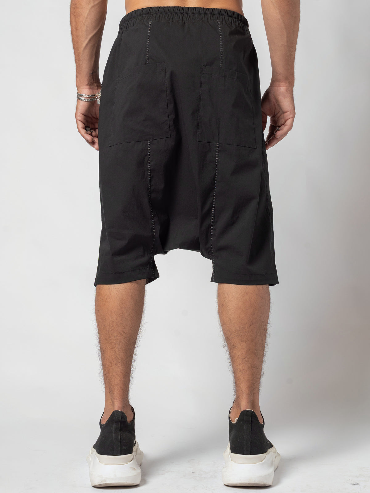 AITO Drop-Crotch Cotton Shorts in Black — back view, full length with the arms held away from the body and the feet close together