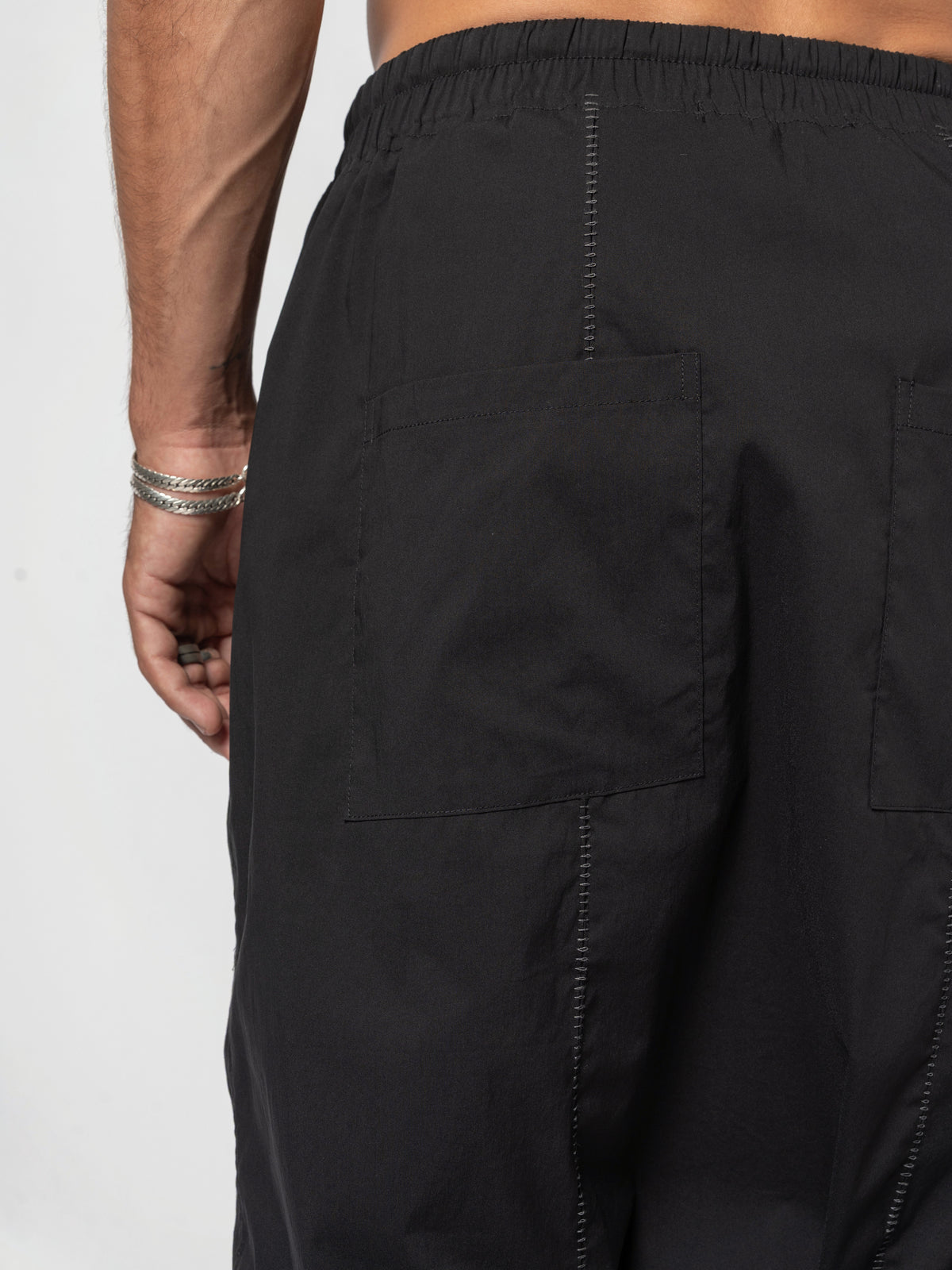 AITO Drop-Crotch Cotton Shorts in Black — close-up of the back waistband and centre back seam, one patch pocket running off the edge of the frame