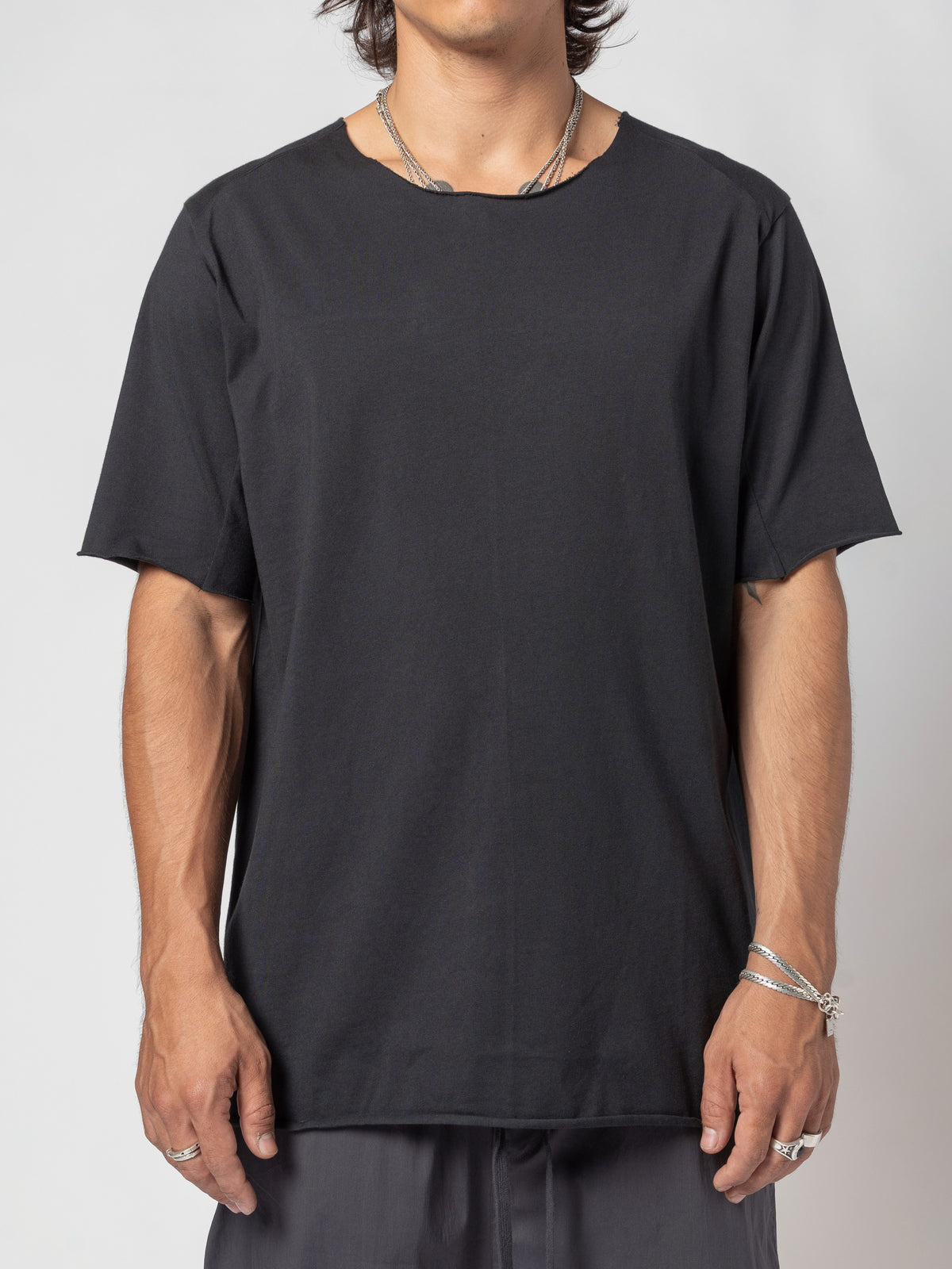AITO Scar Stitch Cotton T-Shirt in Black — front view of the torso cropped at the jaw, arms resting against the body, hem level over dark shorts
