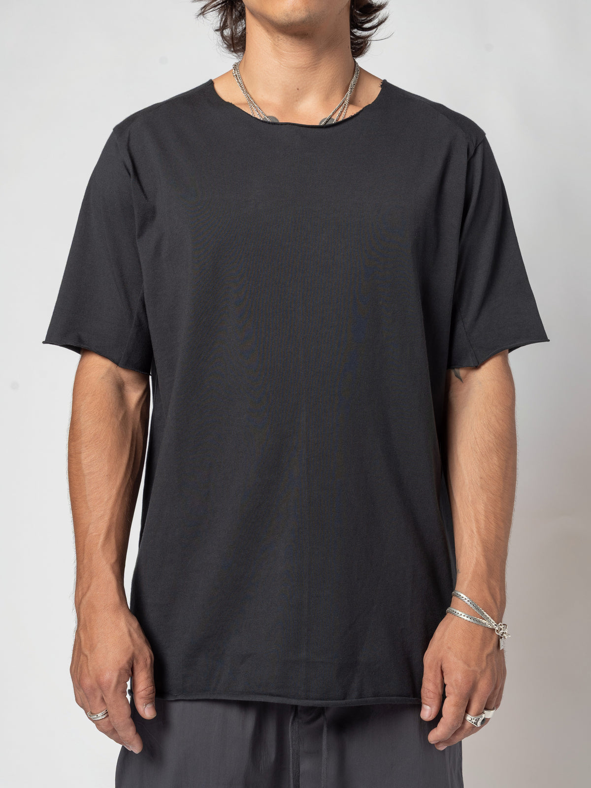 AITO Scar Stitch Cotton T-Shirt in Black — front view from slightly further back, both hands hanging clear of the hips, the full shoulder line in frame