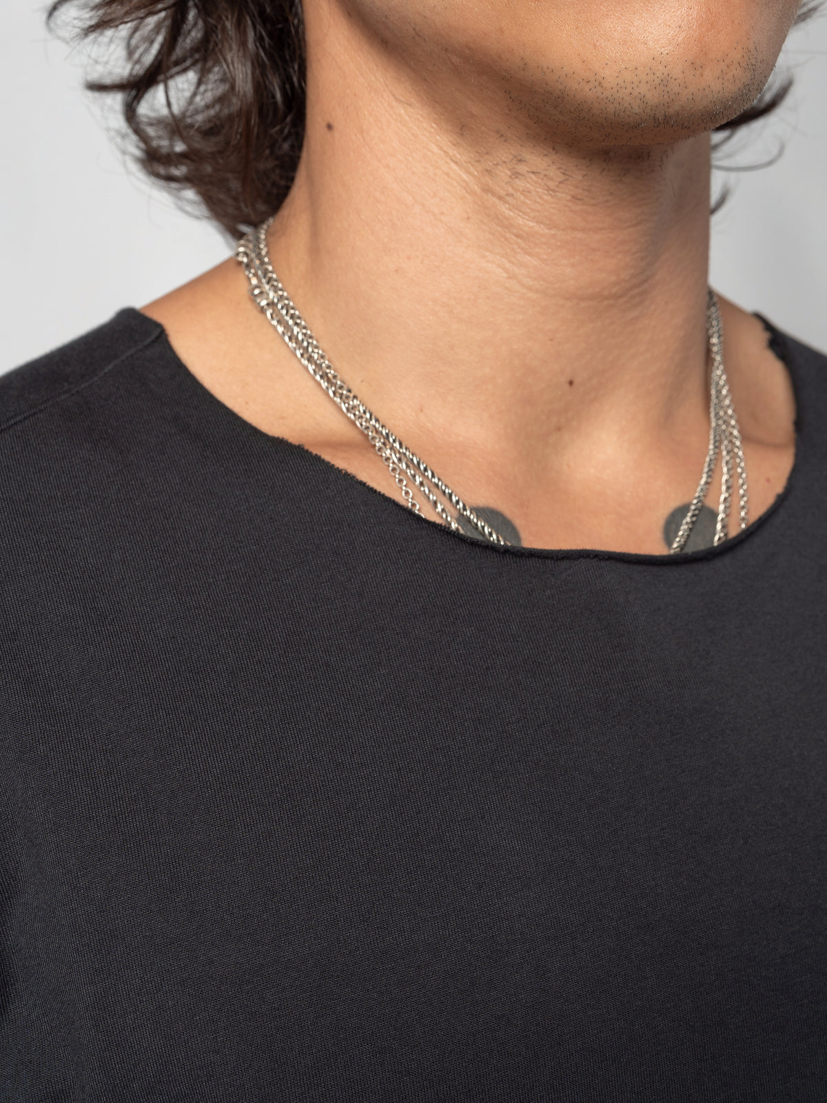 AITO Scar Stitch Cotton T-Shirt in Black — close-up of the neckline at the collarbone, cut wide and left with a raw edge