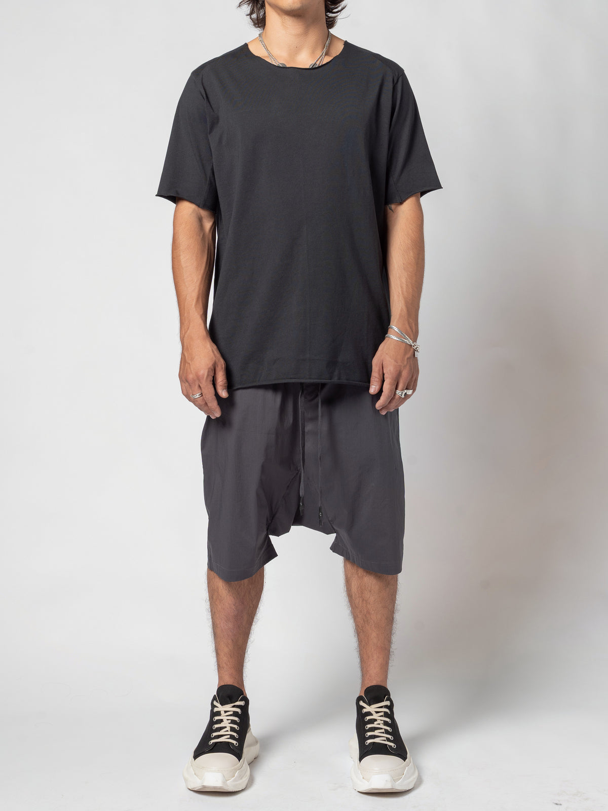 AITO Scar Stitch Cotton T-Shirt in Black — full-length front view, standing square, worn loose over dark drop-crotch shorts