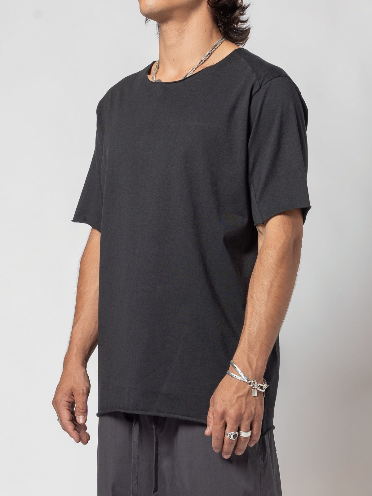 AITO Scar Stitch Cotton T-Shirt in Black — side view of the torso, the side seam and the straight hem falling past the waistband