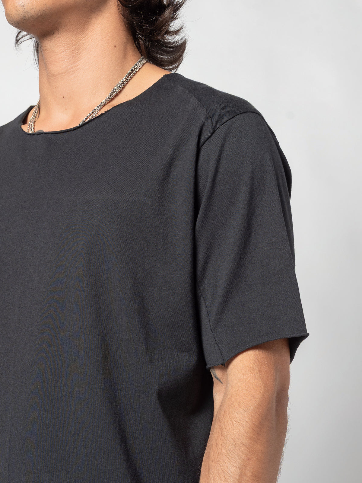 AITO Scar Stitch Cotton T-Shirt in Black — close-up of the shoulder and sleeve from the side, the seam curving down towards the underarm