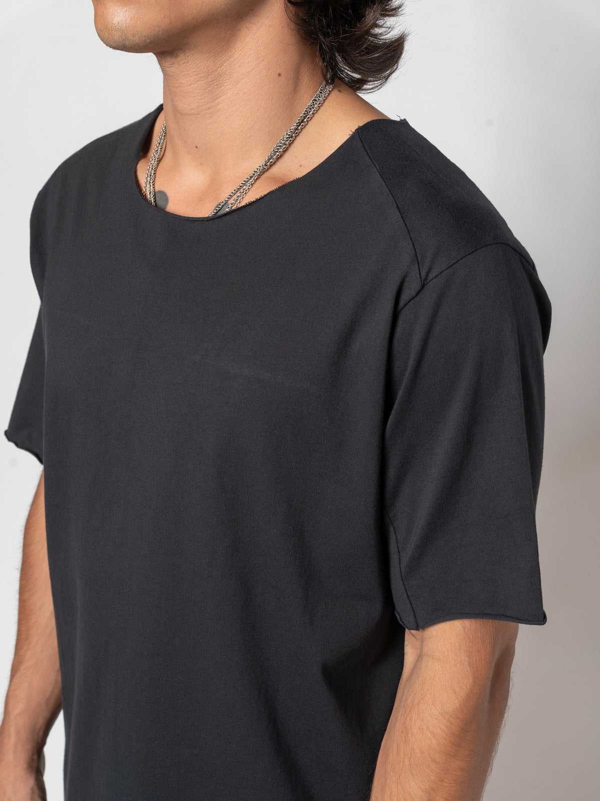 AITO Scar Stitch Cotton T-Shirt in Black — three-quarter view with the chin lifted and the head turned away, the sleeve opening at the elbow
