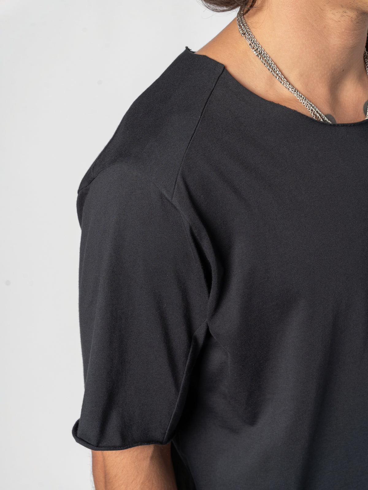 AITO Scar Stitch Cotton T-Shirt in Black — close-up of the upper sleeve with the arm bent, the sleeve opening turned towards the camera