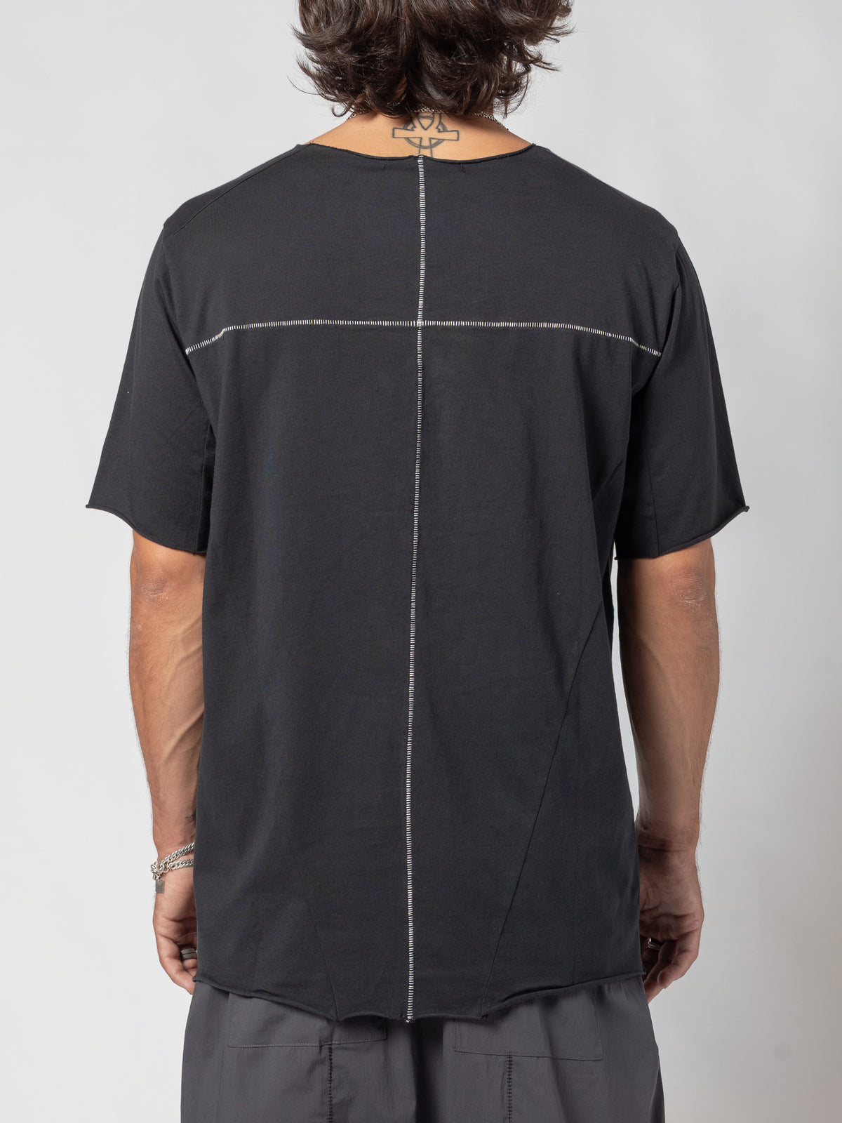AITO Scar Stitch Cotton T-Shirt in Black — back view of the torso, pale contrast stitching crossing the shoulder blades and running down to the hem