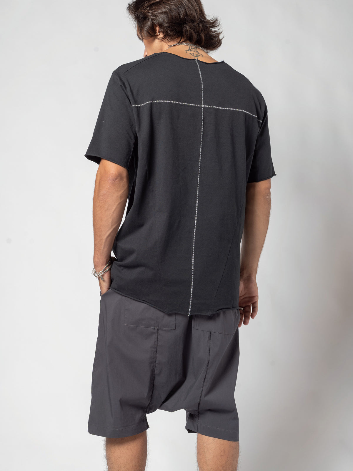 AITO Scar Stitch Cotton T-Shirt in Black — three-quarter back view from his left, the back seam and the hem falling over the shorts