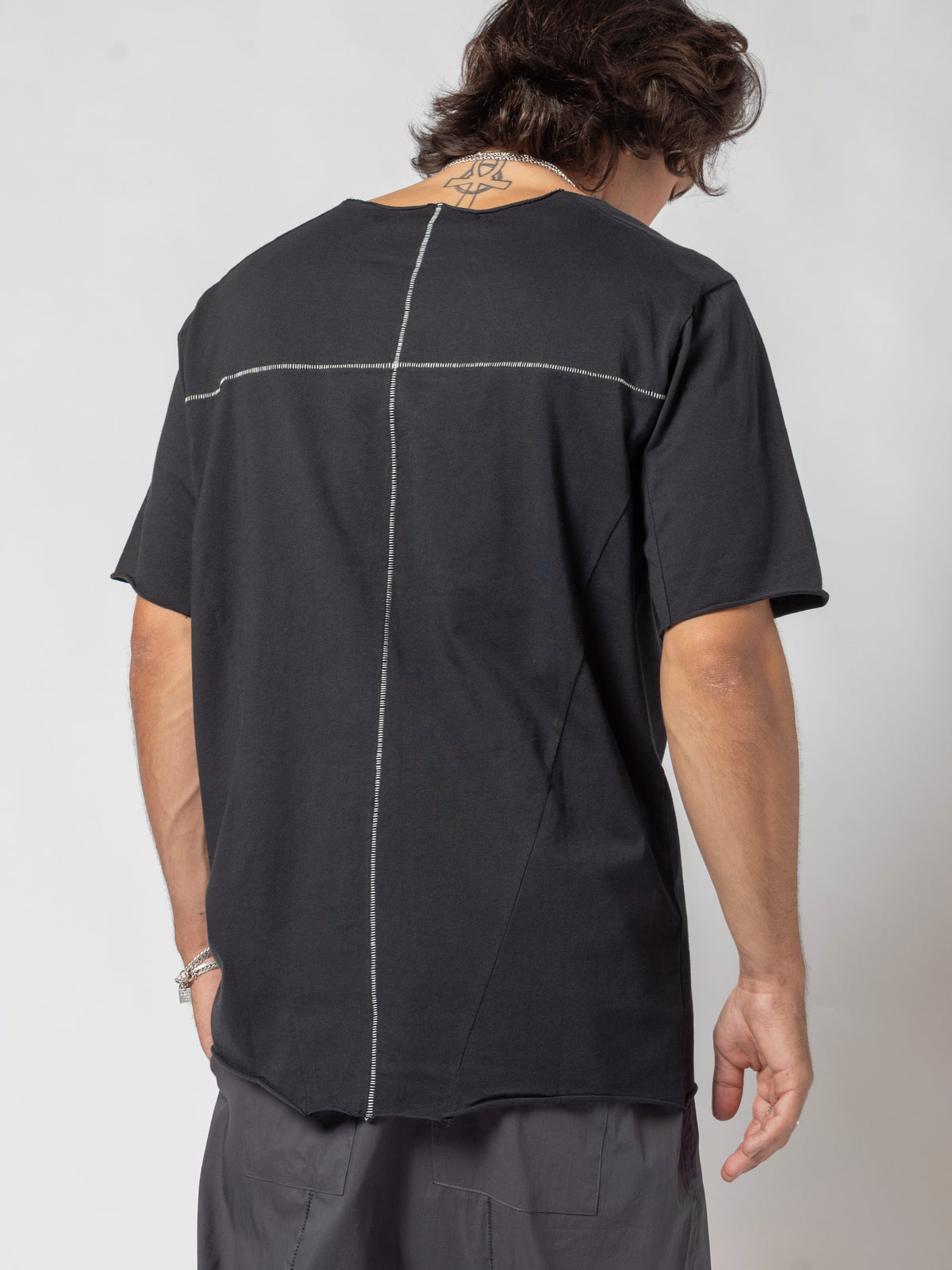 AITO Scar Stitch Cotton T-Shirt in Black — back view turned so his face shows past the shoulder, right arm held away from the body