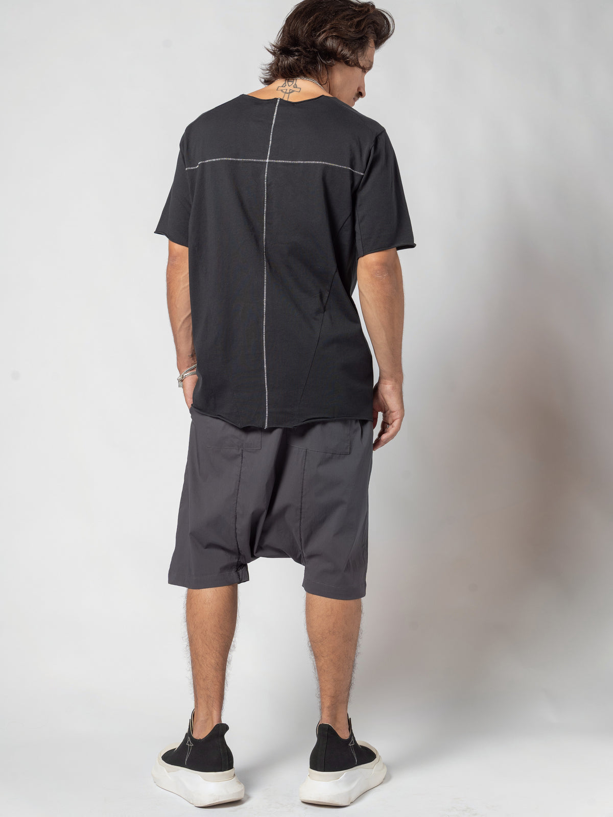 AITO Scar Stitch Cotton T-Shirt in Black — full-length back view with the head turned to the side and one shoulder dropped forward