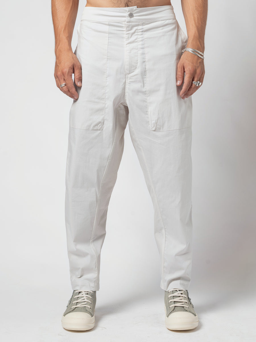 AITO Pleated Drop-Crotch Pants in Off White — straight front from the waistband to the shoes, arms at the sides, hem breaking over the trainers
