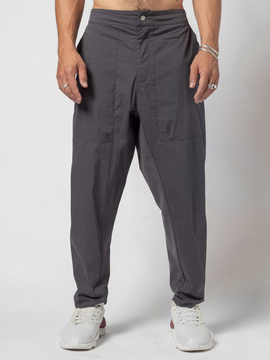 AITO Pleated Drop-Crotch Pants in Dark Grey — full front, hands loose at the sides, waist button and centre-front seam visible