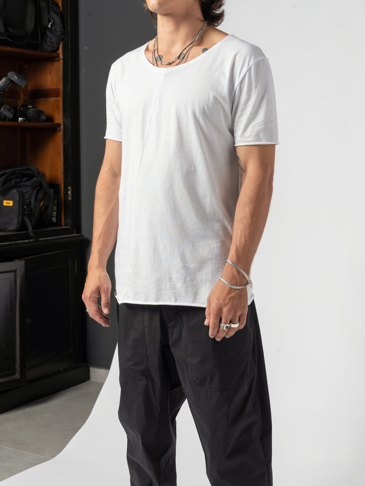 AITO Scoop Neck Cotton T-Shirt in White — full-length front, standing against the dark shelving at the edge of the studio