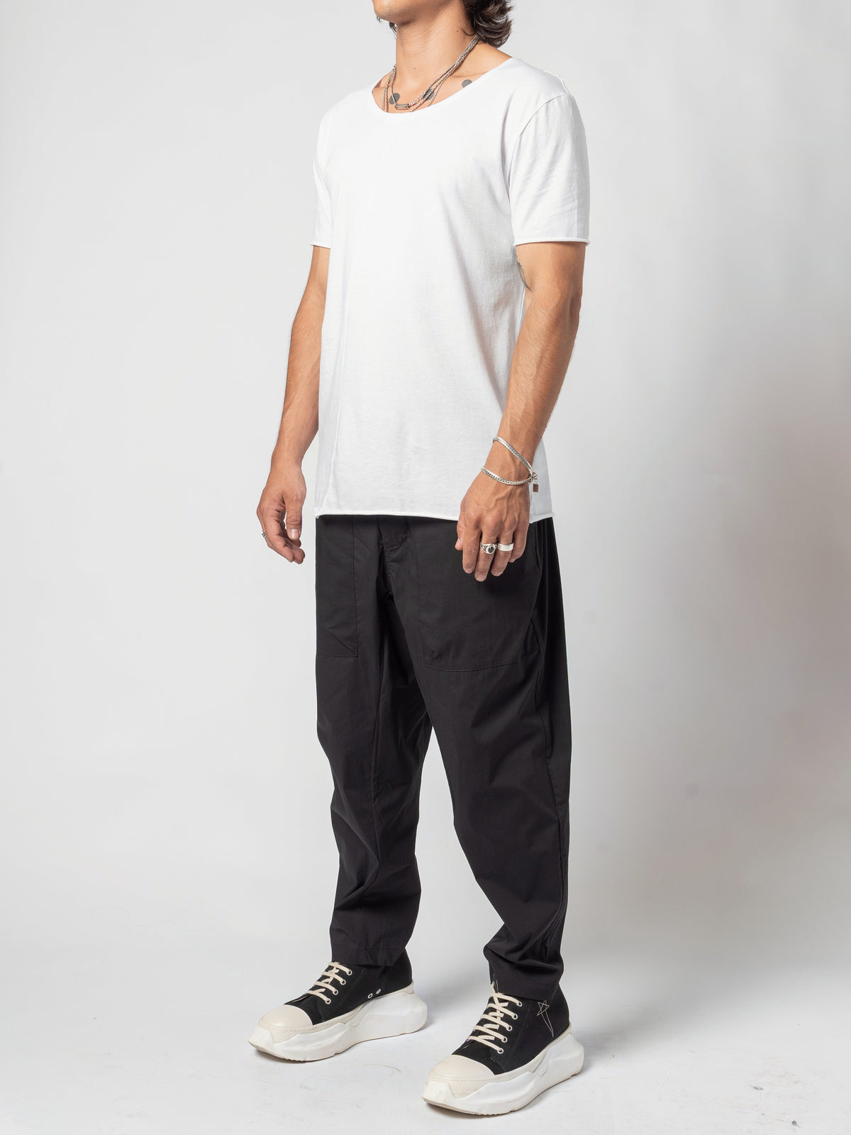 AITO Scoop Neck Cotton T-Shirt in White — full-length three-quarter, the shirt worn loose over black trousers and trainers