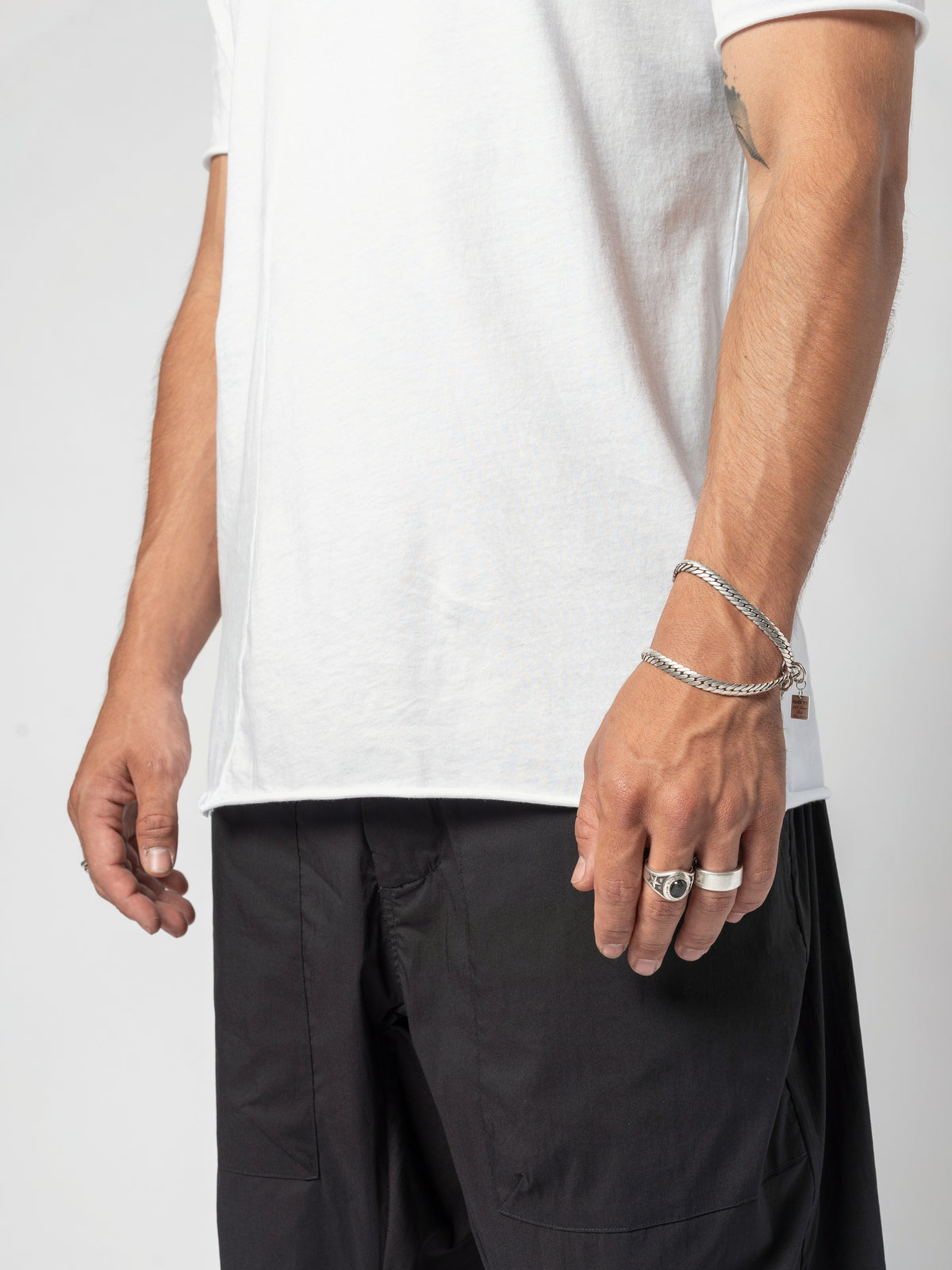 AITO Scoop Neck Cotton T-Shirt in White — close-up of the hem and one hand at the hip, the shirt falling over the waistband
