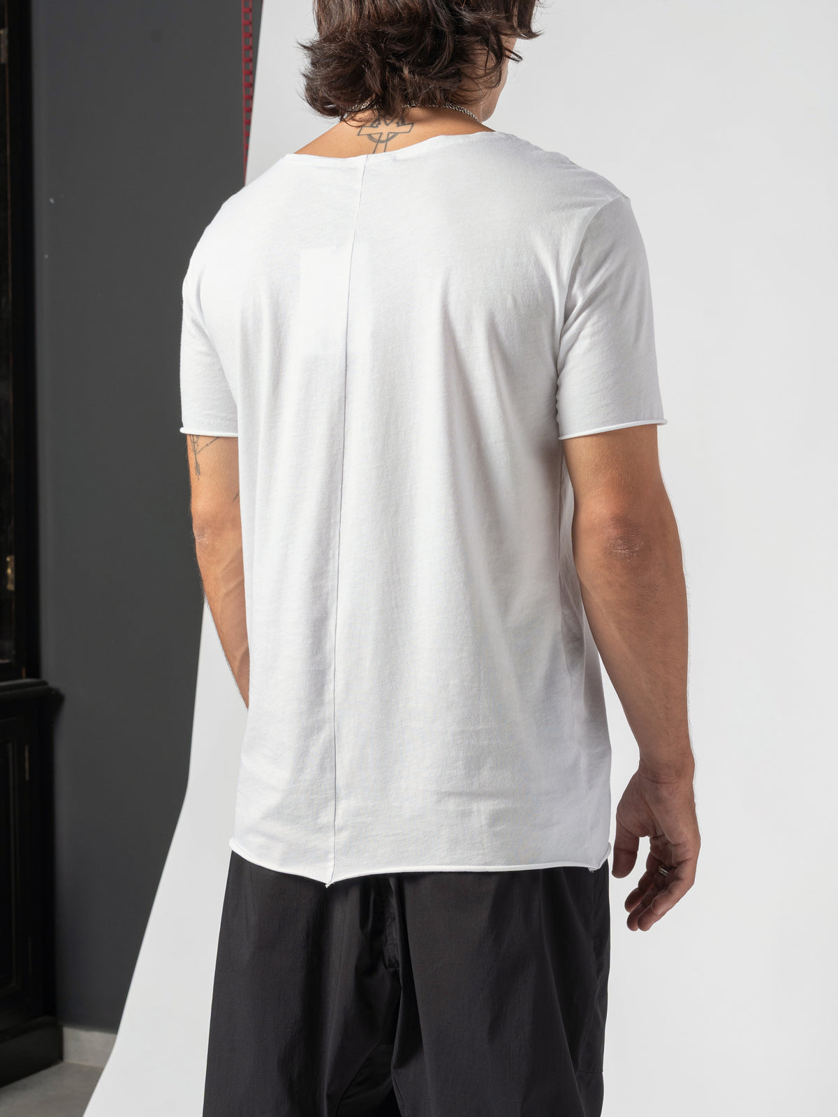 AITO Scoop Neck Cotton T-Shirt in White — back three-quarter against the dark studio wall, side and back seen together
