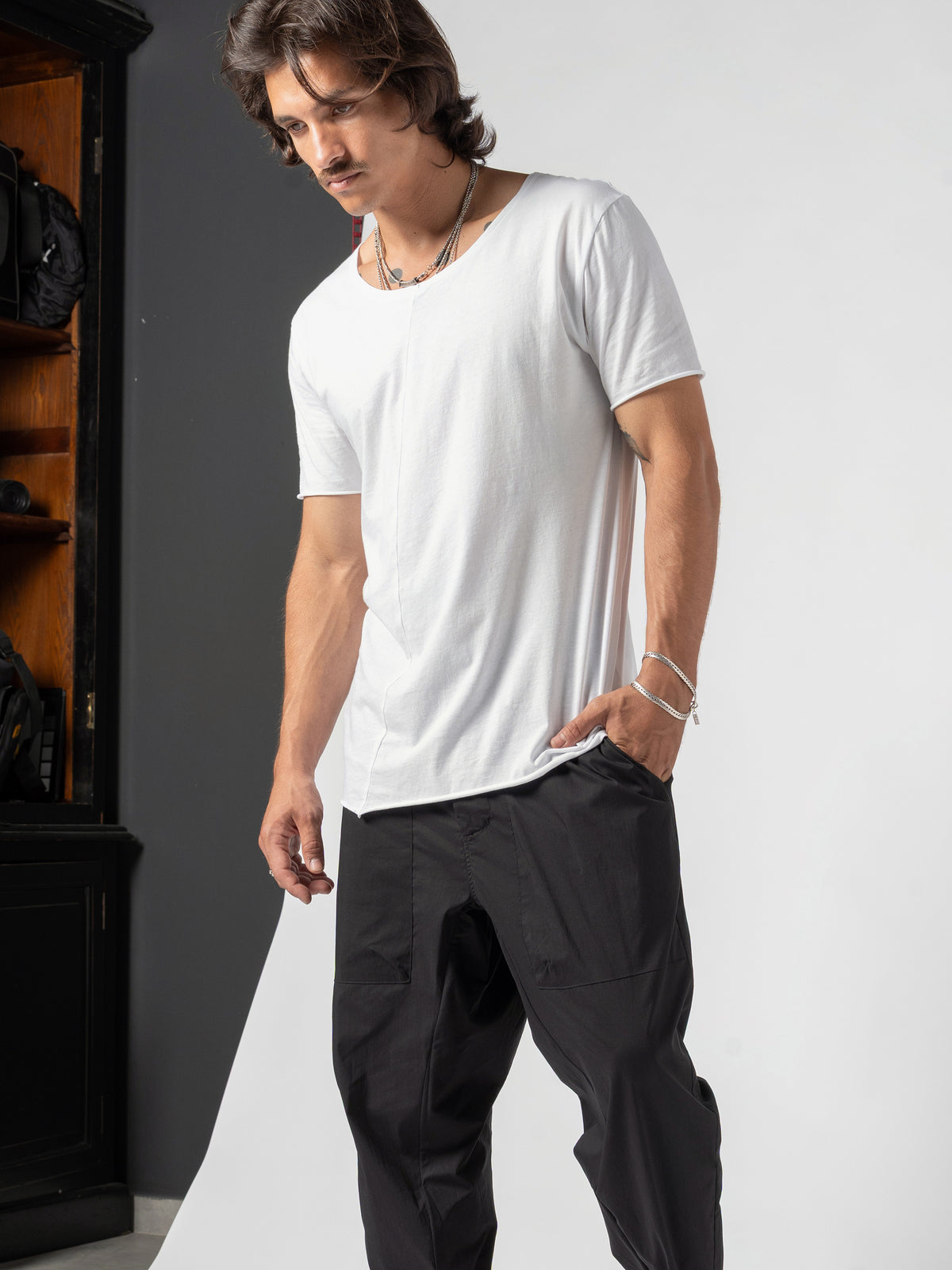 AITO Scoop Neck Cotton T-Shirt in White — torso to the knee, head turned down to the floor, one hand pushed into the pocket