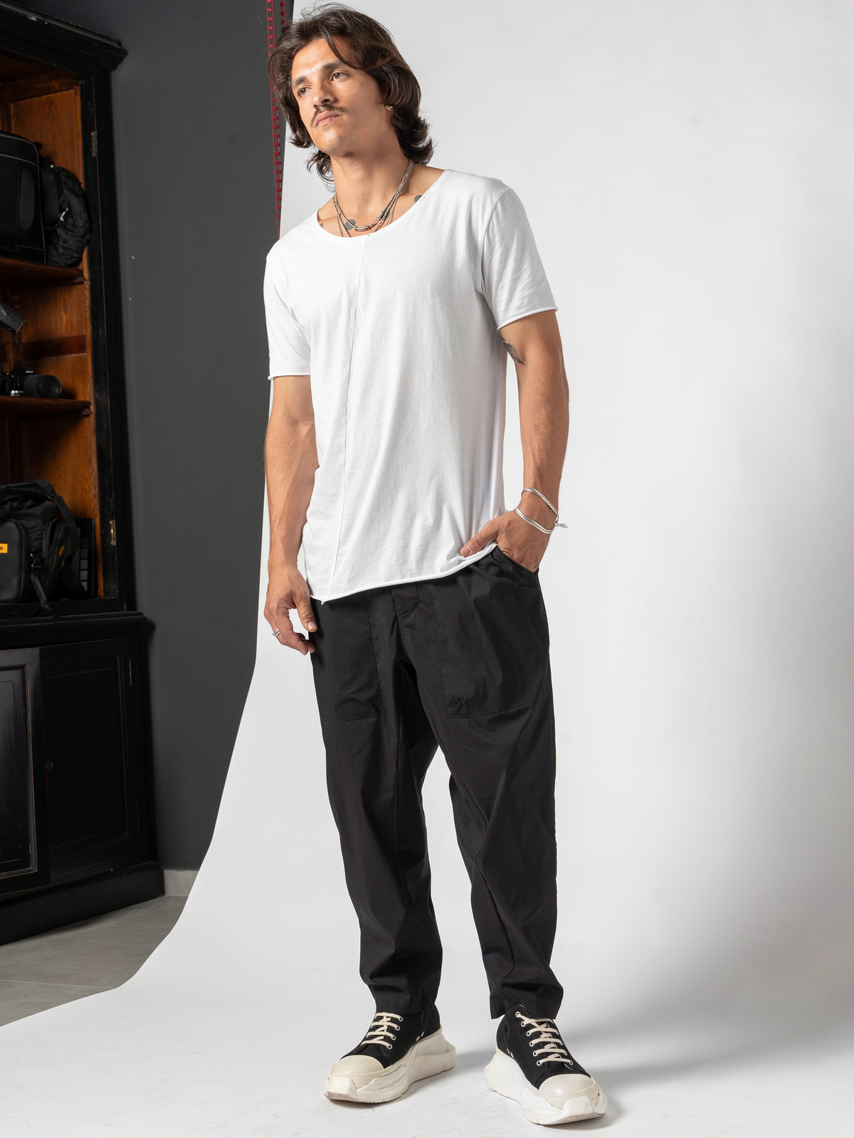 AITO Scoop Neck Cotton T-Shirt in White — full-length with the head turned up and away, one hand in the trouser pocket