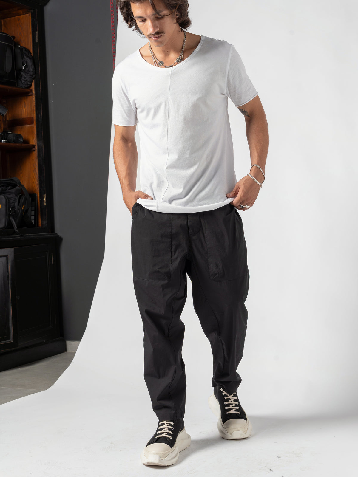 AITO Scoop Neck Cotton T-Shirt in White — full-length front with the weight on one leg, head turned aside, hands in the pockets