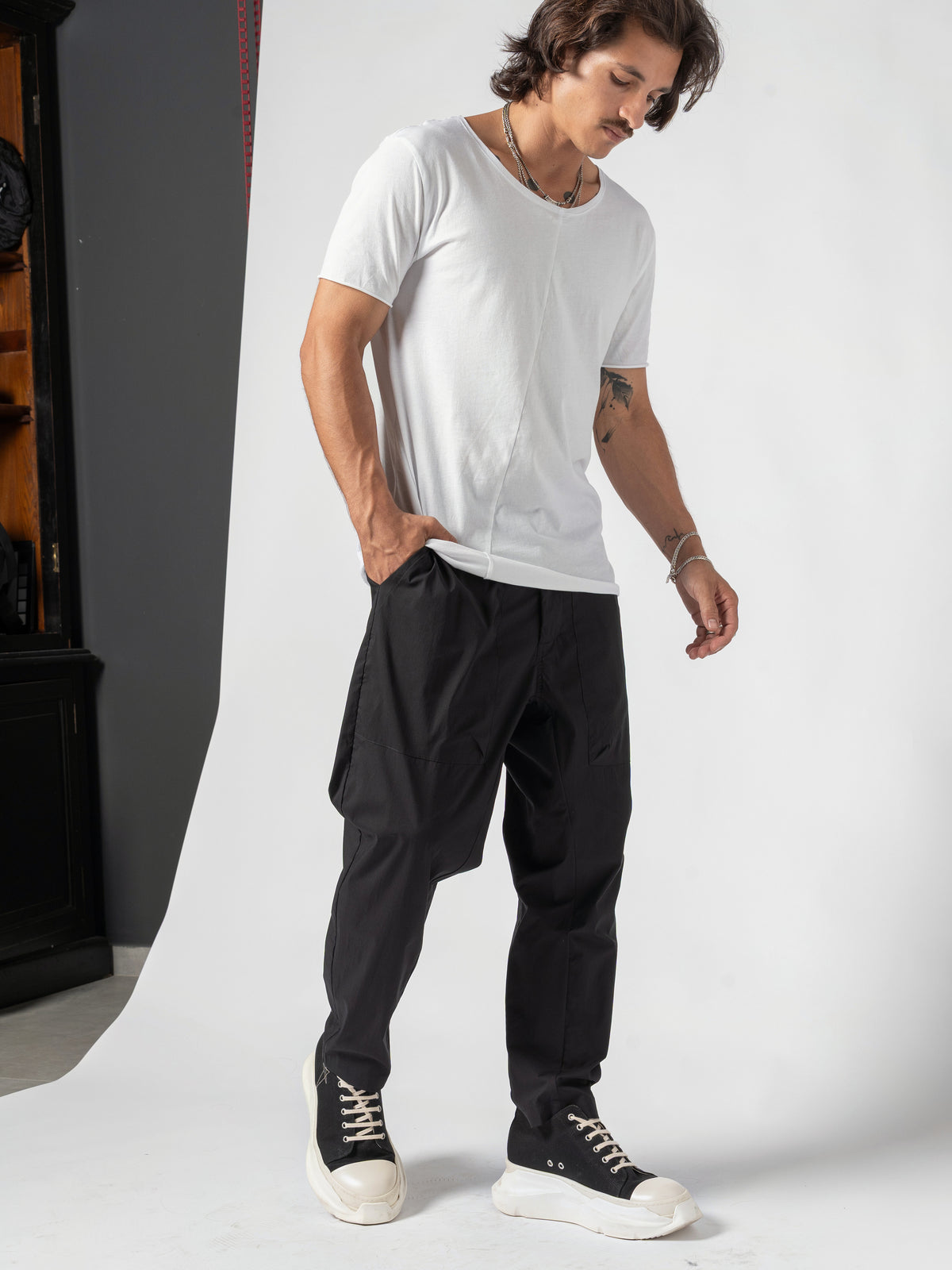 AITO Scoop Neck Cotton T-Shirt in White — full-length three-quarter, head turned down over the shoulder, one hand in the pocket