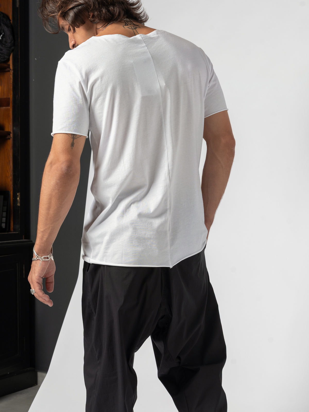 AITO Scoop Neck Cotton T-Shirt in White — back three-quarter, head turned down and away, the longer back hem falling below the hip