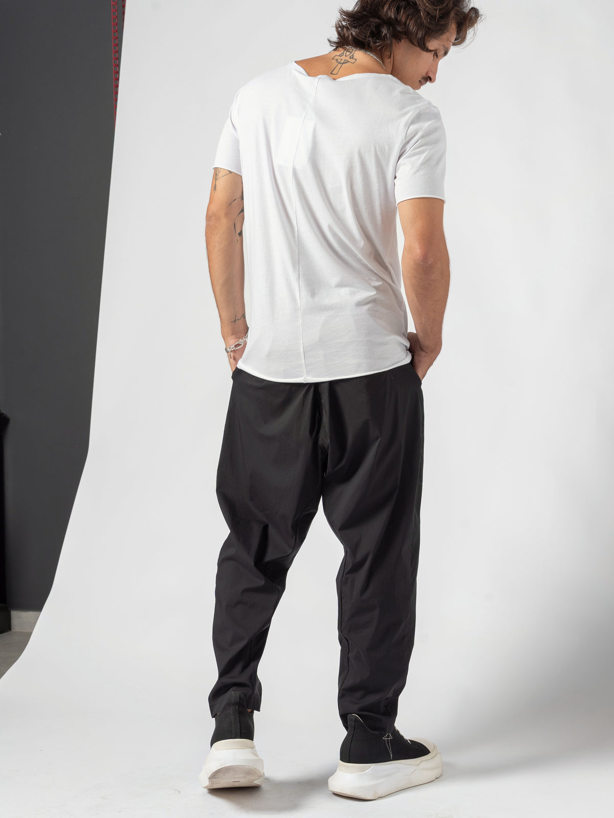 AITO Scoop Neck Cotton T-Shirt in White — full-length back three-quarter, looking back over the shoulder, one hand in the pocket