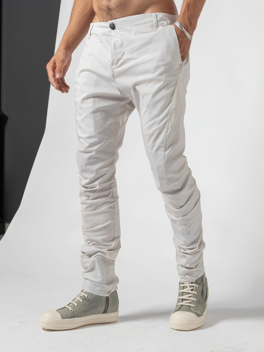 AITO Stacked Hem Slim Pants in Off White — three-quarter front mid-step, a hand in the pocket and the weight on the front leg