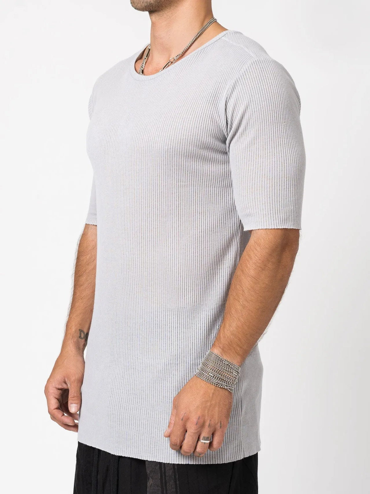 AITO Ribbed Cotton T-Shirt in Light Grey — three-quarter side view on model, the vertical rib and raw-cut hem falling past the hip.