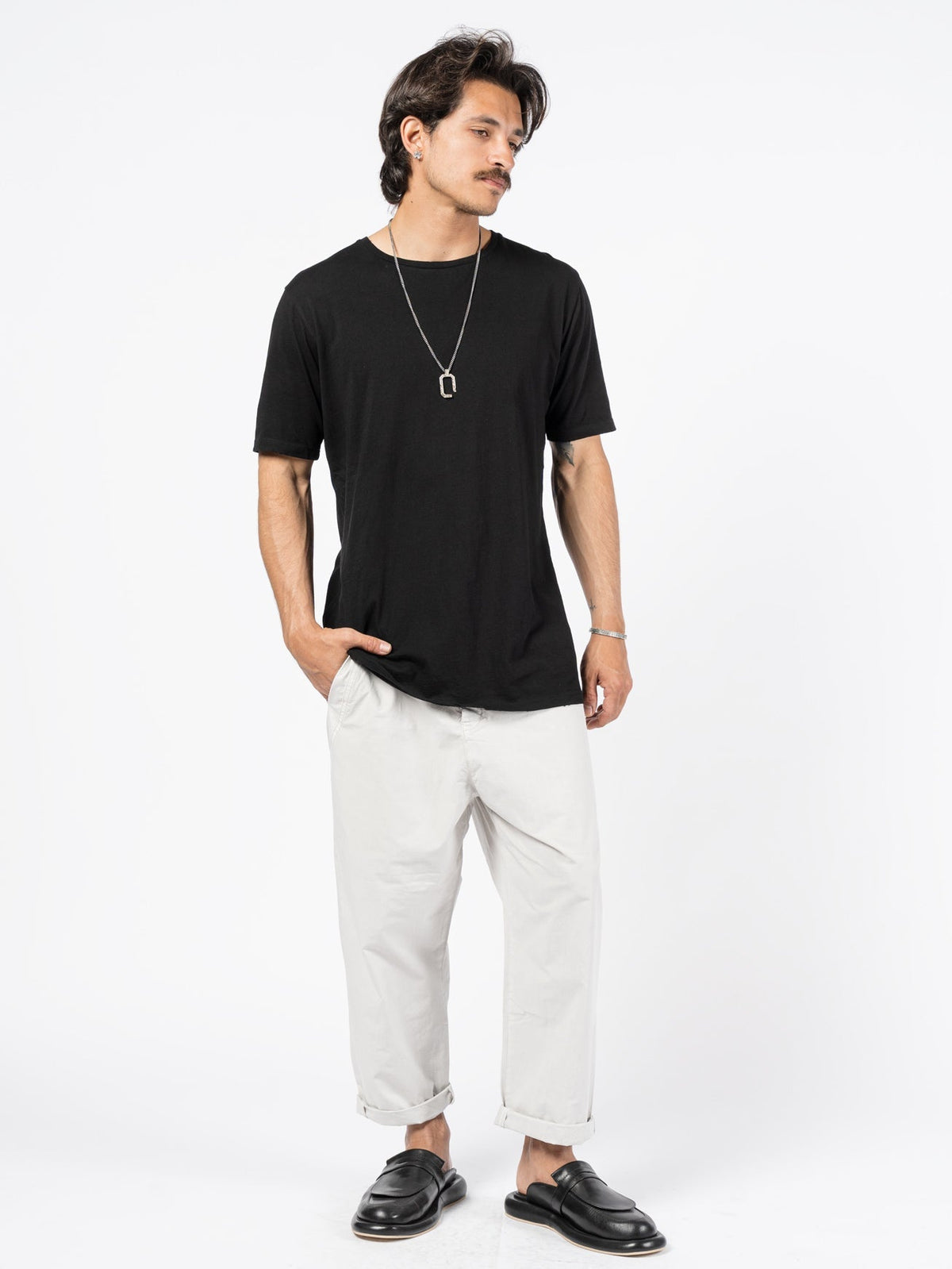AITO Washed Cotton T-Shirt in Black — full-length front view on model, showing the longline curved drop hem